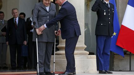 Le pr&eacute;sident fran&ccedil;ais Fran&ccedil;ois Hollande essaie d'attraper les b&eacute;quilles de la chanceli&egrave;re allemande Angela Merkel &agrave; son arriv&eacute;e au Palais de l'Elys&eacute;e &agrave; Paris, le 19 f&eacute;vrier 2014. (BENOIT TESSIER / REUTERS)