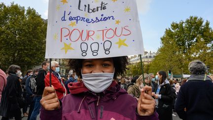 Une jeune fille tient une pancarte "Liberté d'expression pour tous" lors d'un reassemblement place de la République à Paris,&nbsp;en hommage à Samuel Paty, le 18 octobre 2020. (LAURENCE KOURCIA / HANS LUCAS / AFP)