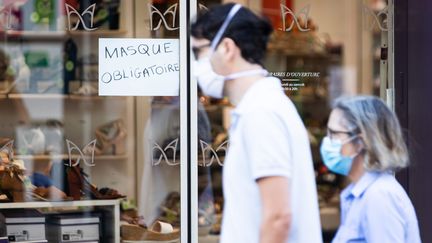 Des passants masqués devant une devanture de magasin à Paris où il est indiqué "masque obligatoire", le 21 juillet 2020 (photo d'illustration). (ALEXIS SCIARD  / MAXPPP)