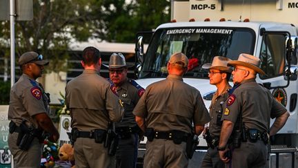 Des policiers parlent près d'un mémorial improvisé pour les victimes de la fusillade devant l'école primaire Robb à Uvalde, au Texas, le 27 mai 2022. (CHANDAN KHANNA / AFP)