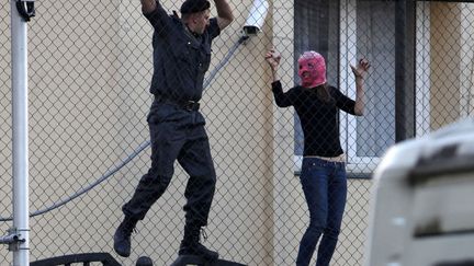 Un policier (G) essaie d'attraper une supportrice du groupe de punk Pussy Riot dans l'ambassade de Turquie&nbsp;situ&eacute;e pr&egrave;s du tribunal de&nbsp;Moscou (Russie), le 17 ao&icirc;t 2012. (ALEXANDER ZEMLIANICHENKO / AP / SIPA)