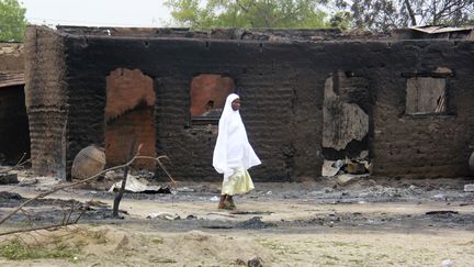 A Baga, une femme passe devant des maisons br&ucirc;l&eacute;es apr&egrave;s une attaque en avril 2013. Boko Haram a &agrave; nouveau attaqu&eacute; cette ville en janvier 2015, tuant des centaines, voire des milliers, de personnes. (  REUTERS)