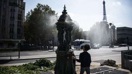 Un enfant cherche à se rafraîchir auprès d'une fontaine à eau à Paris, le 17 août 2023. (MAGALI COHEN / HANS LUCAS / AFP)