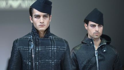 La collection Emporio Armani a une sensibilité urbaine caractérisée par la présence du jersey et l'usage de la maille. Les jerseys aux coupes franches donnent du volume aux cabans et parkas aux finitions mohair. L'innovation des tissus et le goût pour le contemporain sont exprimés dans le tissage en chevron et le jacquard damier dans lequel est tissé un fil d'or et d'argent, interrompu par un coup de pinceau abstrait, référence à l'art traditionnel japonais du Shodo. Le détail qui définit le vêtement est le macro zip. La veste, sans doublure et déstructurée, utilise les détails des bombers tels que le mini col, les poignets, la ceinture en bord côte, portée avec un pantalon de costume. Les vestes sont dérivées en maille compacte camel et zip doré ou avec un gilet incorporé. 
 (TIZIANA FABI / AFP)