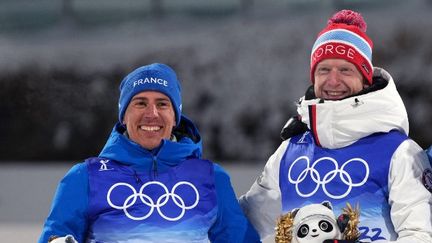 Le biathlète français Quentin Fillon Maillet (à gauche) avec Johannes Boe sur le podium du sprint des Jeux olympiques de Pékin, le 12 février 2022. (RAMIL SITDIKOV / SPUTNIK / AFP)