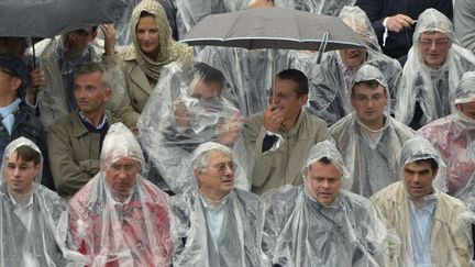 Les spectateurs se prot&egrave;gent de la pluie lors du premier tour du tournoi de tennis de Roland-Garros &agrave; Paris, le 26 mai 2014. (MIGUEL MEDINA / AFP)