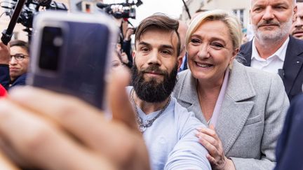 La candidate du RN à l'élection présidentielle, Marine Le Pen, prend la pose pour un selfie, le 18 avril 2022 à Saint-Pierre-en-Auge (Calvados). (SAMEER AL-DOUMY / AFP)