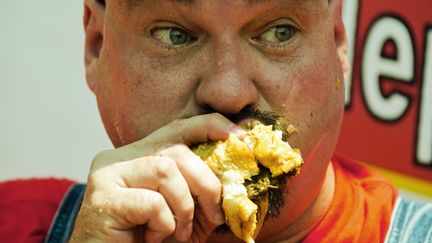 Un homme dévore un hamburger (à un concours !). (JIM WATSON / AFP)