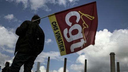 Un gréviste tient&nbsp;un drapeau de la CGT devant la raffinerie de Feyzin (Rhône), le 24 mai 2016. (JEFF PACHOUD / AFP)