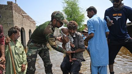 Un soldat aide des victimes des inondations, le 7 septembre 2022 à Dadu (Pakistan). (AAMIR QURESHI / AFP)