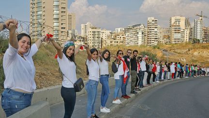 Des Libanais se tiennent la main pour former une chaîne humaine, symbole d'unité nationale dans la protestation, à Beyrouth, au Liban, le 27 octobre 2019. (MARWAN NAAMANI / DPA / AFP)