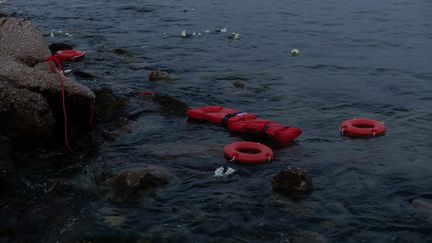 Des membres de la Jeunesse communiste de Grèce lancent des gilets de sauvetage au port du Pirée en Grèce, lors de la Journée mondiale des réfugiés, le 20 juin 2023. (KOSTIS NTANTAMIS / ANADOLU AGENCY / AFP)