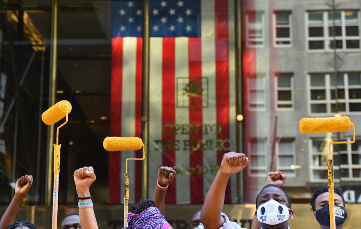 Des militants lèvent leur poings et leurs rouleaux à peinture alors qu'ils peignent le slogan "Black Lives Matter" ("Les vies noires comptent") devant la tour Trump, le 9 juillet 2020 à New York.&nbsp; (ANGELA WEISS / AFP)