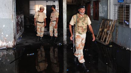 Les forces de s&eacute;curit&eacute; pakistanaises dans un b&acirc;timent incendi&eacute; &agrave; l'a&eacute;roport de Karachi, le 10 juin 2014, au lendemain d'un assaut men&eacute; par un commando taliban. (RIZWAN TABASSUM / AFP)