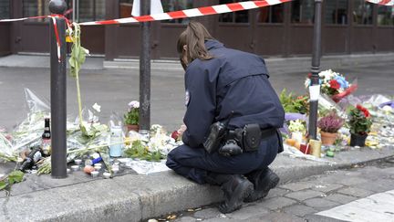 Une policière&nbsp;se recueille devant le café La Bonne Bière, le 14 novembre, à Paris, au lendemain des attentats.&nbsp; (ADRIEN MORLENT / AFP)