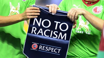 Deux joueurs du Rubin Kazan tiennent un fanion d&eacute;non&ccedil;ant le racisme lors d'un match de Ligue Europa, &agrave; Wigan (Angleterre), le 24 octobre 2013.&nbsp; (ANDREW YATES / AFP)