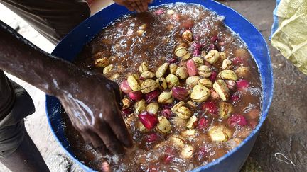 les producteurs en extraient les fèves des cabosses (l’écabossage), puis enlèvent l’enveloppe des noix pour les sécher. Ensuite, elles sont emballées dans des sacs et des paniers de 50 kg.  (Sia Kambou / AFP)