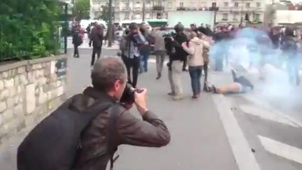 Un jeune homme tombe à terre après le lancement par les policiers d'une grenade de désencerclement, en marge de la manifestation du 26 mai contre la loi Travail à Paris. (GAZARLOIC / TWITTER)