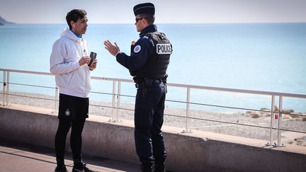 Un policier non masqué contrôle un passant, le 18 mars 2020 à Nice (Alpes-Maritimes). (ARIE BOTBOL / HANS LUCAS / AFP)