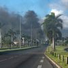 Des fumées au loin sur une route principale de Nouméa (Nouvelle-Calédonie), le 16 mai 2024. (DELPHINE MAYEUR / AFP)