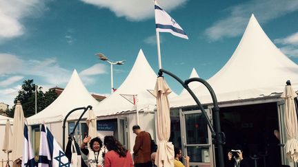 Le pavillon israélien au Festival de Cannes. Au premier plan, Eti Cohen, la directrice du département Films au ministère israélien de la Culture et du sport, fait un signe de la main à des visiteurs qui arrivent sur le stand le jeudi 12 mai 2016. (DR)