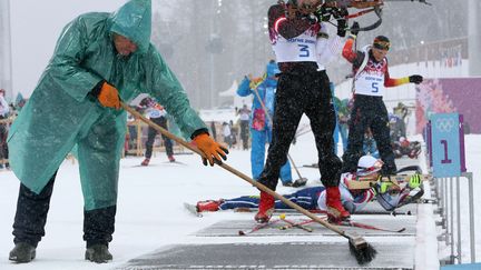 Un membre charg&eacute; de l'entretien des pistes nettoie un tapis devant le pas de tir, durant la mass-start de biathlon masculine, le 18 f&eacute;vrier 2014. (SERGEI KARPUKHIN / REUTERS)