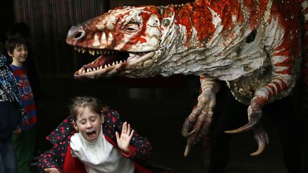 Une petite fille s'enfuit devant la r&eacute;plique anim&eacute;e d'un dinosaure &agrave; Londres (Royaume-Uni), le 18 f&eacute;vrier 2013. (KIRSTY WIGGLESWORTH / AP / SIPA)