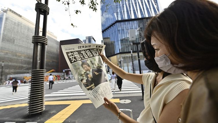 Des Japonais lisent un journal évoquant l'attaque contre Shinzo Abe, alors entre la vie et la mort, à Tokyo, le 8 juillet 2022. Lex-Premier ministre est mort quelques heures plus tard. (DAVID MAREUIL / ANADOLU AGENCY / AFP)