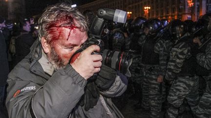 Un photographe de l'agence Reuters, Gleb Garanich, bless&eacute; &agrave; la t&ecirc;te, photographie la manifestation, &agrave; Kiev, en Ukraine, samedi 30 novembre 2013.&nbsp; (REUTERS                            )