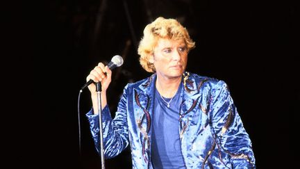 Les vêtements bleus et la crinière blonde, Johnny chante devant son public à Paris, le 15 septembre 1982. (KEYSTONE-FRANCE / GAMMA-KEYSTONE / GETTY IMAGES)