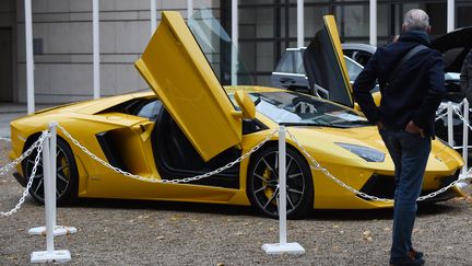 Un homme observe une Lamborghini dans la cour du ministère de l'Économie, dans le cadre d'une vente aux enchères de biens d'exception pour les dix ans de l'Agrasc à Paris, le 5 novembre 2021. Photo d'illustration. (ERIC PIERMONT / AFP)