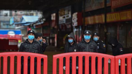 Des policiers gardent l'entrée du marché de gros de fruits de mer de Huanan, à Wuhan (Chine), où le coronavirus a été détecté le 24 janvier 2020, et qui depuis a été fermé par les autorités chinoises.&nbsp; (HECTOR RETAMAL / AFP)