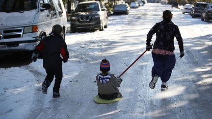 Dans une autre rue de la ville, des enfants ont improvisé une luge pour glisser sur la chaussée verglacée. (JOE RAEDLE / GETTY IMAGES NORTH AMERICA)