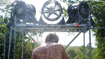 Un jeune homme profite d'un brumisateur, le 4 janvier, sur le site du festival des Eurock&eacute;ennes de Belfort, qui ont eu lieu sous une forte chaleur.&nbsp; (SEBASTIEN BOZON / AFP)