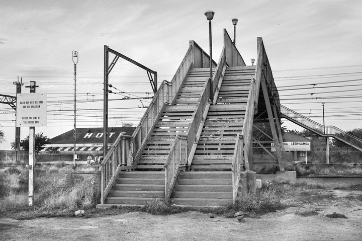 David Goldblatt, "Passerelle enjambant la voie ferrée, Leeu Gamka, province du Cap-Est, 30 août 2016 Passerelle enjambant la voie ferrée Le Cap-Johannesburg, avec double escalier séparé pour «blancs » et « non blancs », conformément à la loi no 49 sur les équipements publics séparés (Reservation of Separate Amenities Act) de 1953. Aujourd’hui, l’apartheid n’existe plus. Les panneaux indiquant
	les files séparées ont été retirés vers 1992, mais le pont demeure, au service d’une population d’environ 1 500 personnes." Courtesy David Goldblatt et Goodman Gallery Johannesburg et Cape Town
 (David Goldblatt)