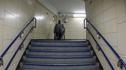 Capture d'&eacute;cran montrant un&nbsp;handicap&eacute; sur un fauteuil bloqu&eacute; devant des escaliers de la station de m&eacute;tro&nbsp;Cannon Stree,t &agrave; Londres. Vid&eacute;o publi&eacute;e le 24 septembre 2014 (THEFREEHELPGUY / YOUTUBE)