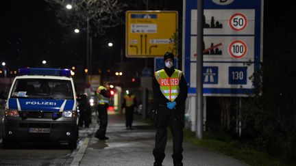 Un policier allemand portant un masque contre le coronavirus Covid-19 contrôle les véhicules à la frontière franco-allemande, entre Strasbourg et Kehl (Bas-Rhin), le 12 mars 2020.&nbsp; (PATRICK HERTZOG / AFP)