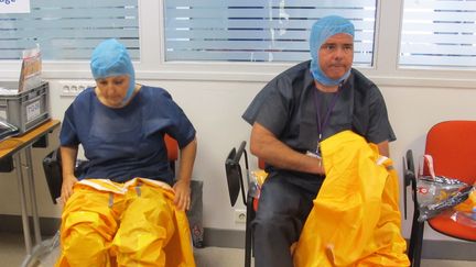 Deux membres du personnel m&eacute;dical du Samu de Paris enfilent la combinaison protectrice qu'ils doivent utiliser pour traiter les cas "possibles" d'Ebola, vendredi 24 octobre 2014, &agrave; l'h&ocirc;pital Necker, &agrave; Paris. (LOUIS BOY / FRANCETV INFO)