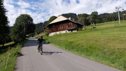 Un cycliste et un chalet en pleine nature à&nbsp;Morzine (Haute-Savoie). (RICHARD VILLALON / MAXPPP)