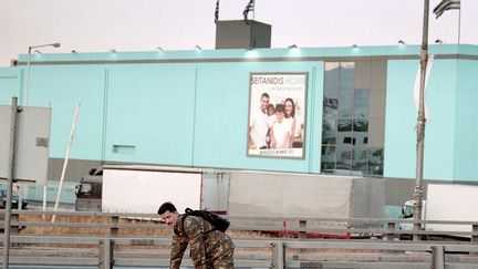 Yannis Karpouzis a reçu l'an dernier le Prix découverte de Photoespaña. Au Centro de Arte Alcobendas, dans la périphérie nord de Madrid, il fait un parallèle entre le temps de la crise financière dans son pays, la Grèce, et le temps de la photographie, qui tous les deux immobilisent les choses. Dans le même lieu, le photographe espagnol Alberto García-Alix expose les photos de son séjour à Paris en 2003 ("París, nada más", "Paris, rien de plus"). Ici, Yannis Karpouzis, Scène de rue : un soldat rentre chez lui. De la série "La crise parallèle, 2010-2016" 
 (Yannis Karpouzis)