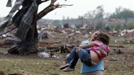 Une femme porte une petite fille extraite des d&eacute;combres de l'&eacute;cole &eacute;l&eacute;mentaire. La plupart des enfants ont pu se r&eacute;fugier dans un abris anti-tornade mais au moins 20 &eacute;l&egrave;ves sont morts.&nbsp; (SUE OGROCKI / AP / SIPA )