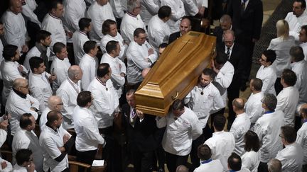 Des chefs portent le cercueil de Paul Bocuse et d'autres se recueillent en silence, vendredi 26 janvier, dans la cathédrale Saint-Jean à Lyon. (PHILIPPE DESMAZES / POOL / AFP POOL )