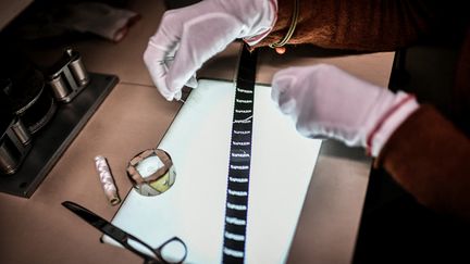 Laure Marchaut, avec ses outils, qui travaille sur une pellicule du film "Napoléon", d'Abel Gance.&nbsp; (STEPHANE DE SAKUTIN / AFP)