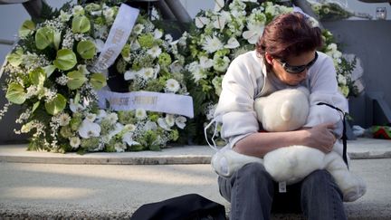 Une femme tient un ours en peluche au cours de la c&eacute;r&eacute;monie qui a eu lieu le 21 mars 2012 &agrave; Lommel (Belgique) en hommage aux victimes de l'accident du car belge en Suisse. (KRISTOF VAN ACCOM / BELGA / AFP)