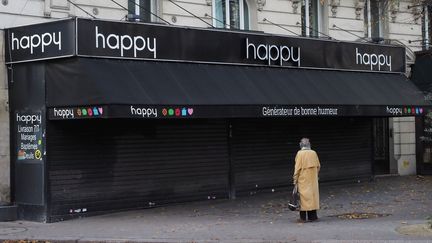 Une personne se tient devant un magasin de fleurs fermé en raison du confinement, à Paris, le 2 novembre 2020. (XAVIER FRANCOLON/SIPA)