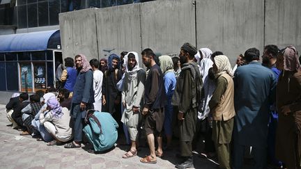 Des Afghans font la queue à l'entrée d'une banque pour retirer de l'argent, dans le quartier de&nbsp;Shar-e-Naw à Kaboul, le 4 septembre 2021. (WAKIL KOHSAR / AFP)