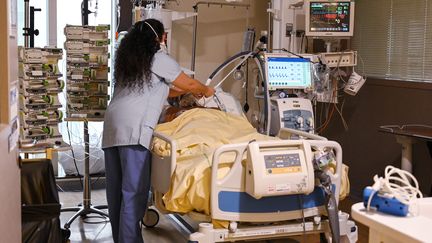 Une soignante s'occupe d'un patient atteint de Covid-19 dans&nbsp;le service de soins intensifs de l'hôpital Avicenne, à Bobigny (Seine-Saint-Denis), le 8 février 2021. (BERTRAND GUAY / AFP)