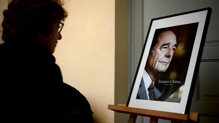 Une femme se recueille devant un portrait de l'ancien président, Jacques Chirac, le 29 septembre 2019. (PHILIPPE LOPEZ / AFP)