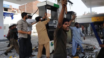 Des Pakistanais s'en prennent &agrave; une station-essence lors d'une manifestation &agrave; Lahore, le 26 mars 2012. (ARIF ALI / AFP)