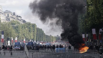 Une poubelle en feu sur l'avenue des Champs-Elysées, à Paris, le 14 juillet 2019. (KENZO TRIBOUILLARD / AFP)